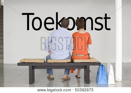 Rear view of couple seated on bench reading Dutch text 