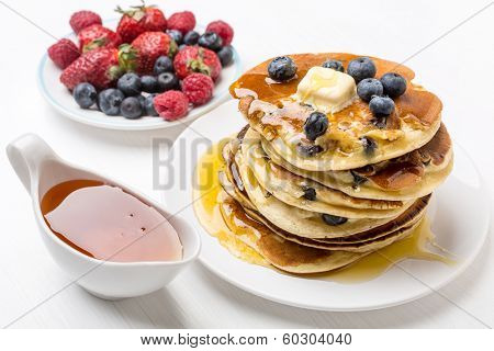 Big Pile of American Blueberry Pancakes with Berries and Maple Syrup