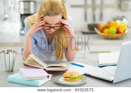Stressed Young Woman Studying In Kitchen