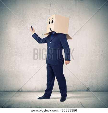 Businessman using mobile phone wearing carton box on head