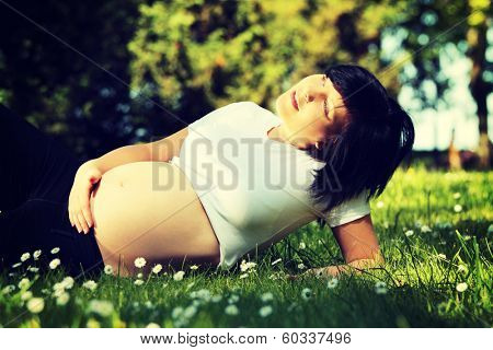 Beautiful teen pregnant woman relaxing in the park