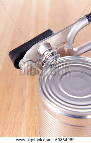 Can piercer with canned on wooden background