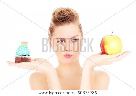 A picture of a woman trying to make a decision between cupcake and apple over white background