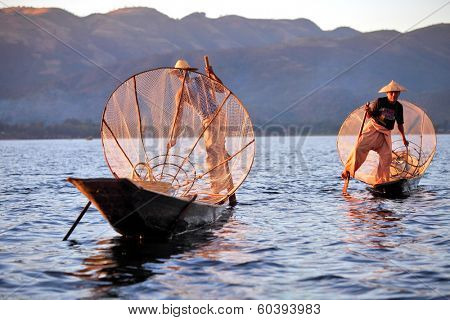 INLE LAKE, MYANMAR - DECEMBER 12, 2013: Fishermen at Inle Lake, Shan State, Myanmar Intha people possess the leg-rowing style and the unique coop-like fishing equipment