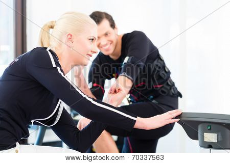 Female coach giving man and woman ems electro muscular stimulation exercise 