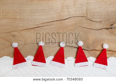 Red Christmas Hats On Wooden Background For A Greeting Card