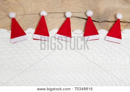 Red Christmas Hats On Wooden Background For A Greeting Card