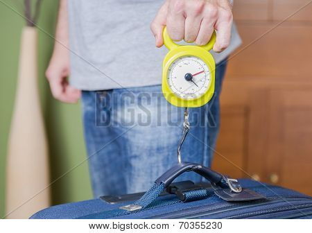 Man checking luggage weight with steelyard balance