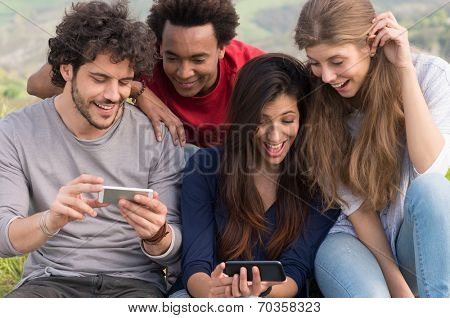 Group Of Laughing Friends With Cellphone Outdoor