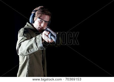 Man aiming a shotgun wearing protective gear