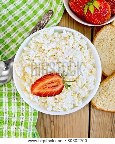 Curd with strawberries in bowl on wooden board
