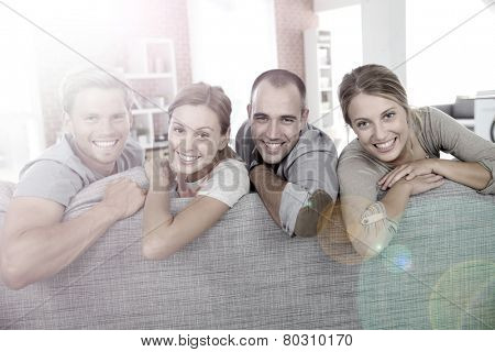 Cheerful roommates sitting in sofa at home