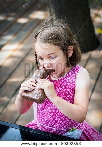 Little Girl Biting Into A Chocolate Bunny