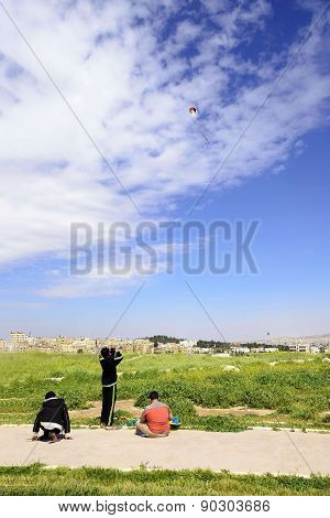 View of three jordanian boys playing with kite in Amman Citadel, Jordan