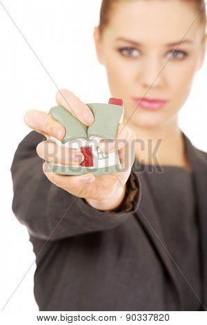 Aggresive businesswoman crushing small house.