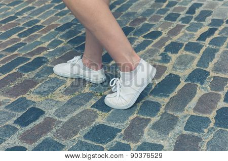 Legs Of Woman Standing On Cobbled Street