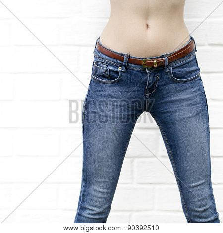 Part of the body, blue jeans for women on the background wall against the white brick white wall
