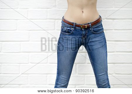 Part of the body, blue jeans for women on the background wall against the white brick white wall