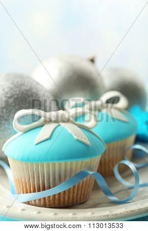 Tasty cupcakes with bow and Christmas toys on color wooden background