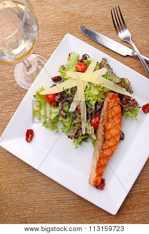 Grilled Salmon With Cheese And Vegetable Salad On White Plate