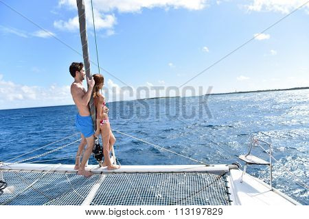 Couple standing in catamaran net looking at scenery