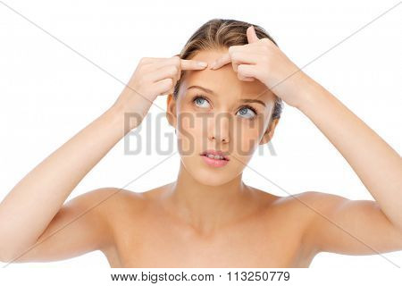 young woman squeezing pimple on her face