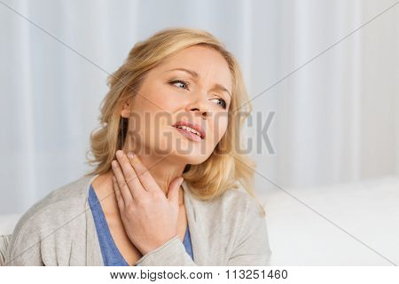 unhappy woman suffering from throat pain at home