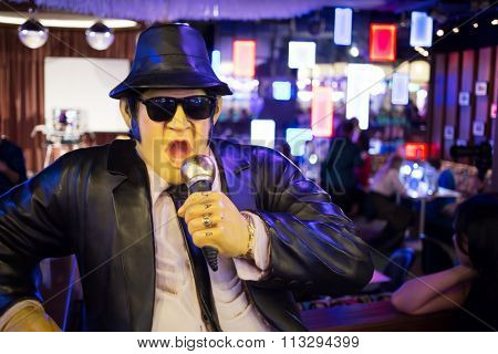 Waxwork singer in black suit and hat in bar interior