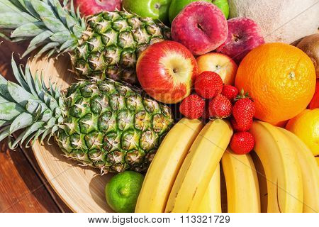 plate with different fruits, like pineapple, orange, apple, bananas and so on