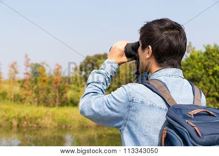 The back view of Man use of the binocular