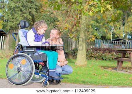 Disability a disabled child in a wheelchair relaxing outside together with a care assistant