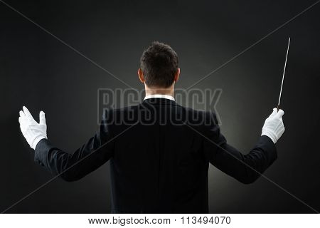 Rear View Of Music Conductor Holding Baton