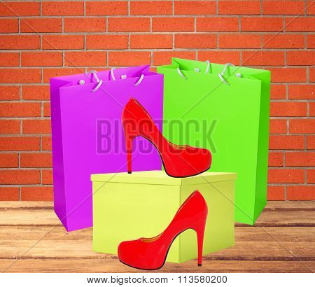 Red Woman Shoe, Yellow Gift Box And Shopping Bags On Wooden Floor Over Brick Wall