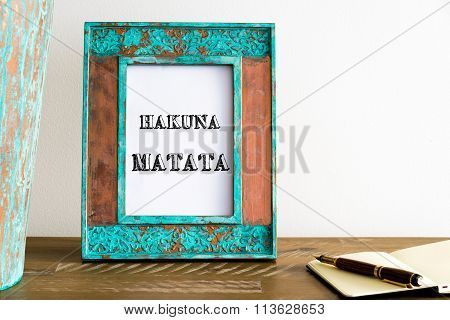 Vintage Photo Frame On Wooden Table With Text Hakuna Matata