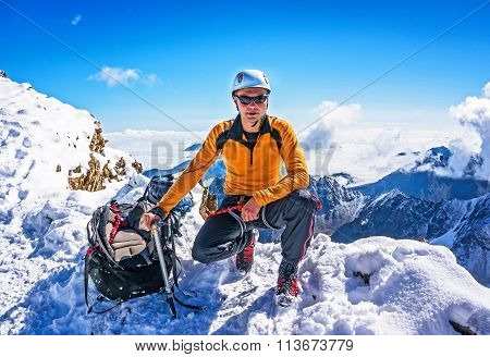 Climber On A Mountain Top Posing On The Background Of Snowy Mountains