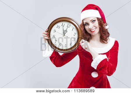 Time Concept And Ideas. Gleeful Red-haired Santa Helper With Big Round Clock And Showing Time. Posin