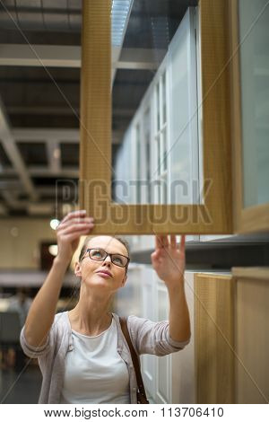 Pretty, young woman choosing the right furniture for her apartment in a modern home furnishings store (color toned image; shallow DOF)