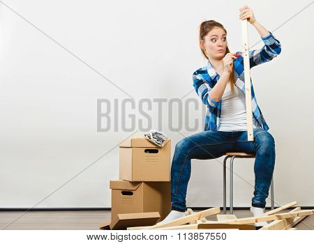 Woman Moving Into Apartment Assembly Furniture.