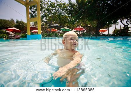 Small Blonde Girl Swim Transparent Water Of Pool