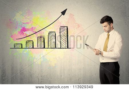 A businessman in modern stylish elegant suit standing on a small ladder and drawing pie and block charts on grey wall background with exponential progressing curves, lines, circles, blocks, numbers