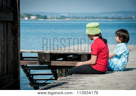 Girld and boy on lake dock in Italy