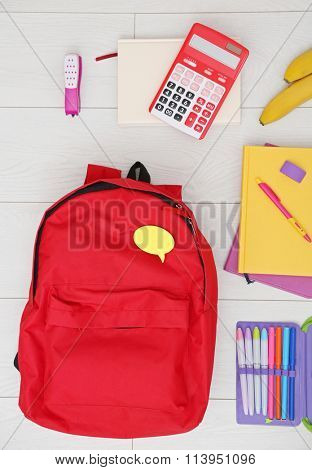 School set with backpack and supplies on light wooden background