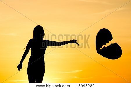 A woman throwing a way a big broken heart