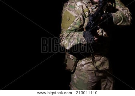 soldier in camouflage with a gun on a black background
