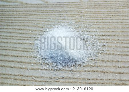 Blurred crumbled white sugar on wooden board background, top view