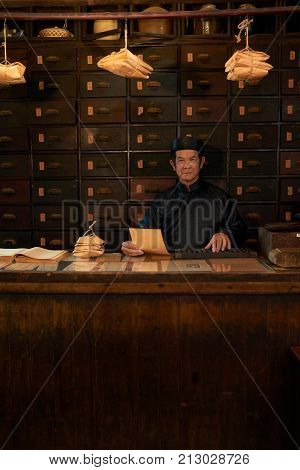 Portrait of traditional Asian medicine practitioner in apothecary