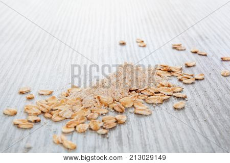 Pile of oat flour with oat flakes on wooden table. Celiac flour alternative. Oat flour.