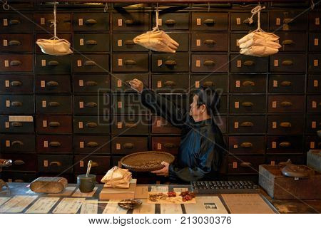 Apothecary worker opening drawer to take out main ingredient