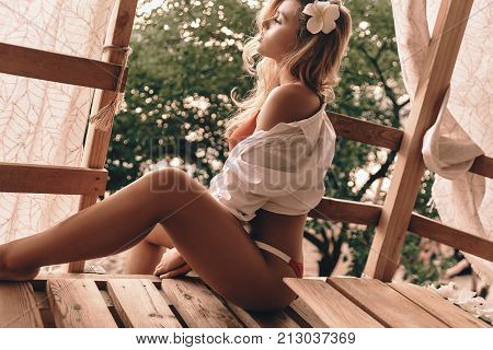 Carefree and relaxed. Attractive young woman in swimwear relaxing while sitting in the tree house outdoors