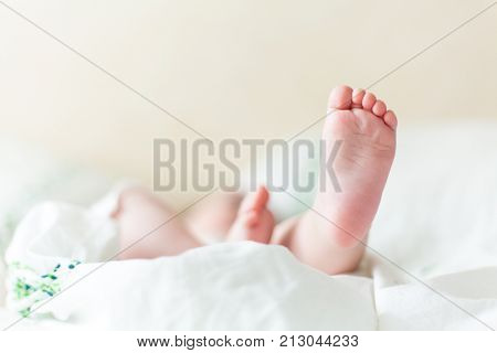 Baby feets, heels, hands in white bed